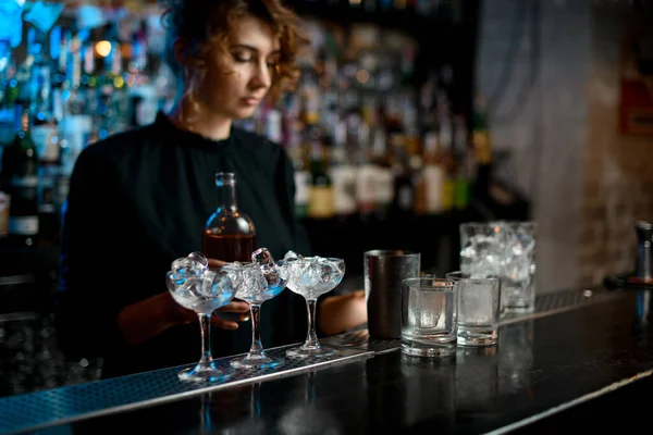 Jovem mulher no bar segura garrafa com bebida na mão . — Fotografia de Stock