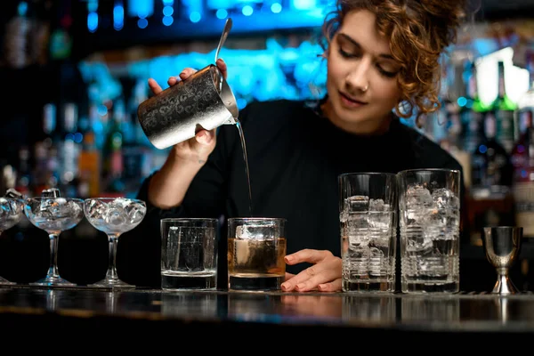Young barman woman carefully pours finished cocktail into glass. — Stock Photo, Image
