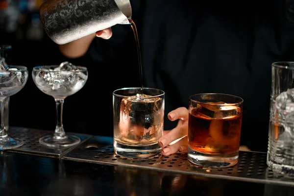 Close-up barman cuidadosamente derrama coquetel acabado em vidro . — Fotografia de Stock