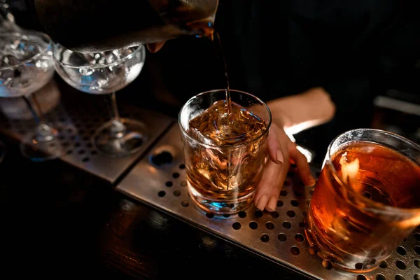 Крупный план бармен аккуратно наливает негрони коктейль в стекло на барной стойке . — стоковое фото