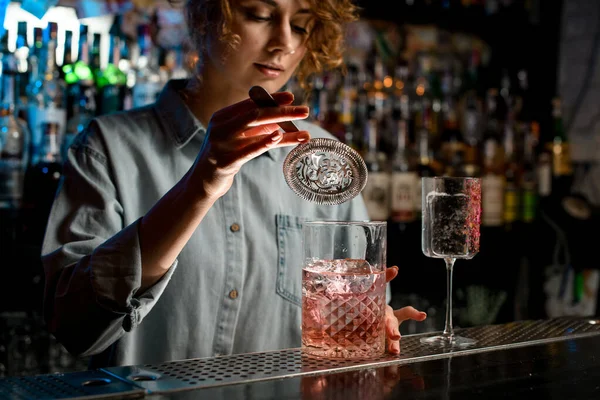 Giovani donne mano tiene colino sopra grande vetro con bevanda rosa — Foto Stock