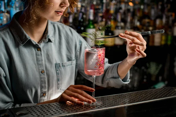 Barman mujer joven decora vidrio con cóctel de rosa por pieza de planta verde . — Foto de Stock