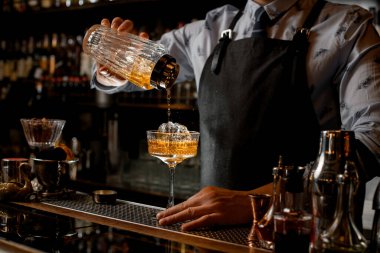 Barmen düzenli olarak bardaktan bardağa soğuk kokteyl doldurur..