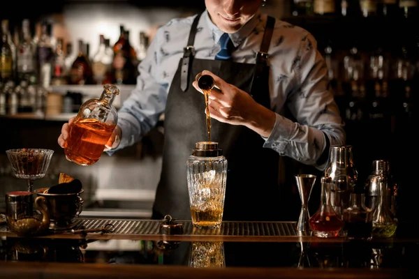 Barman drží láhev s pitím a nalévá tekutinu do třepačky. — Stock fotografie