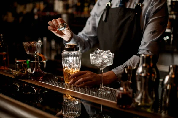 Bartender i baren förbereder cocktail i glasartad shaker — Stockfoto