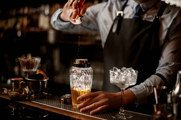 Bartender i svart förkläde häller aktivt upp dryck till glasskak. — Stockfoto