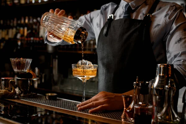 Barman regularly pours finished cold cocktail from glass shaker into wineglass. — Stock Photo, Image