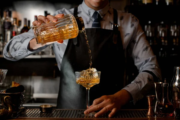 Professionell bartender häller försiktigt färdig kall cocktail från glas shaker i vinglas. — Stockfoto