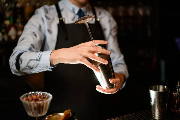 Bartender segura em suas mãos agitador de aço e vidro vazio — Fotografia de Stock