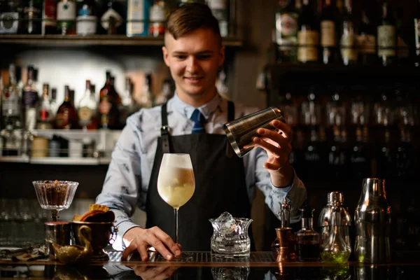 Jovem barman sorrindo segura vidro com coquetel pronto — Fotografia de Stock