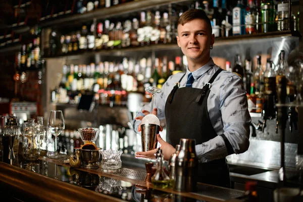 Ung stilig bartender håller i sina händer stål shaker och tomt glas — Stockfoto