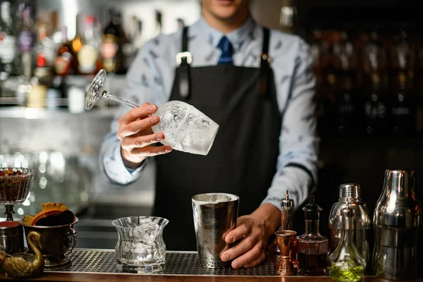 Barkeeper in schwarzer Schürze hält Glas- und Stahlshaker an Bar. — Stockfoto