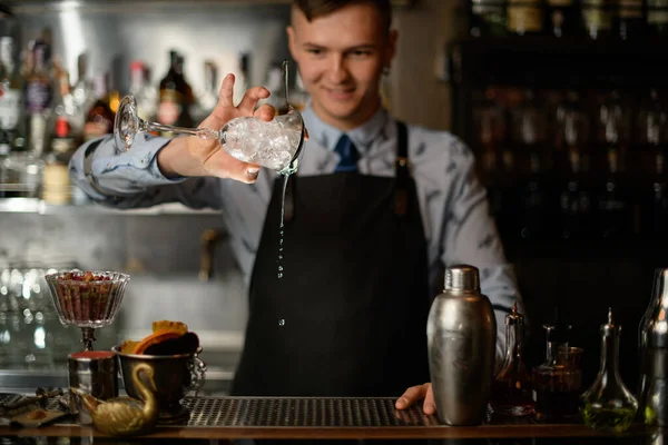 Barman tient le verre à vin avec de la glace et verse du liquide de celui-ci . — Photo