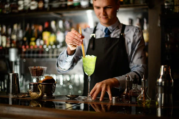 Young smiling barman pours cocktail from shaker into glass with ice. Stock  Photo by ©Fesenko 357395766