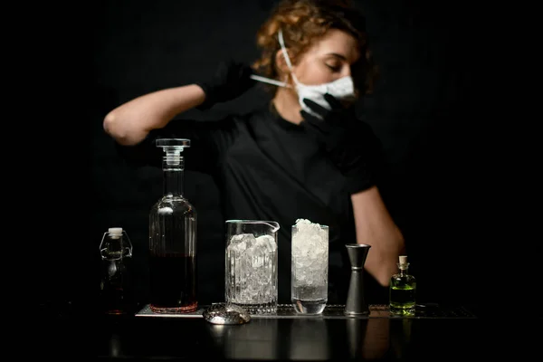 Mujer joven en el bar se pone una máscara médica blanca . — Foto de Stock
