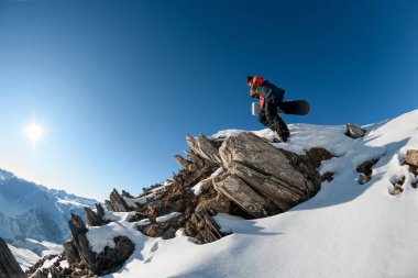 Üstünde snowboardcu adam olan taştan dağın muhteşem manzarası..