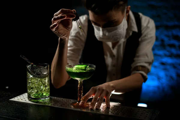 Giovane barista aggiunge con attenzione ingrediente al cocktail — Foto Stock