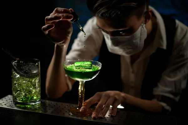 Primer plano. Joven barman añade cuidadosamente ingrediente a cóctel — Foto de Stock
