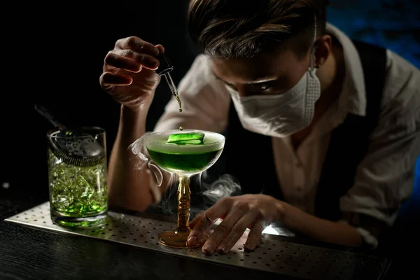 Camarero joven añade cuidadosamente ingrediente al vaso con cóctel de hielo — Foto de Stock