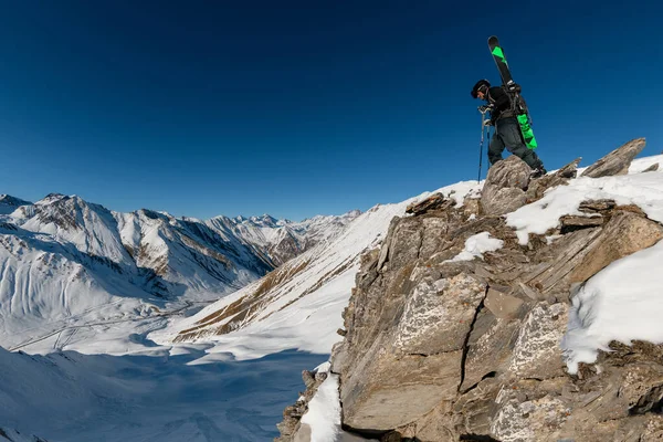 Спортсмен с лыжным снаряжением на спине на скалистой горе — стоковое фото
