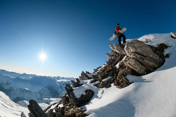 Прекрасный вид на каменную вершину горы с человеком сноубордистом на ней . — стоковое фото