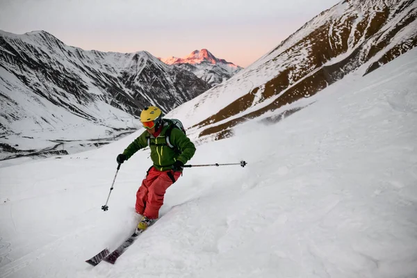 Narciarz schodzi na zboczu góry o zachodzie słońca — Zdjęcie stockowe