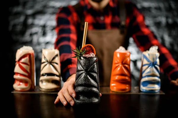 Profesyonel barmen, turunçgil dilimli renkli seramik bardakta içki sunar. — Stok fotoğraf