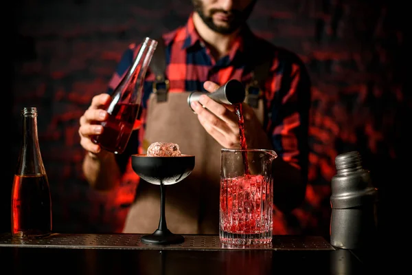 Camarero vierte líquido rojo de jigger en taza de mezcla —  Fotos de Stock