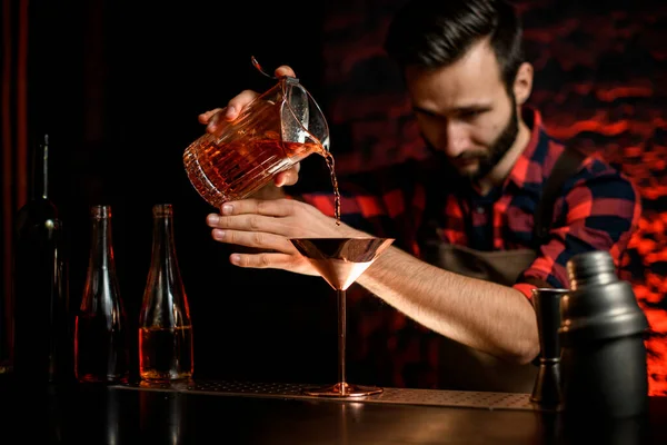 Young smiling barman pours cocktail from shaker into glass with ice. Stock  Photo by ©Fesenko 357395766