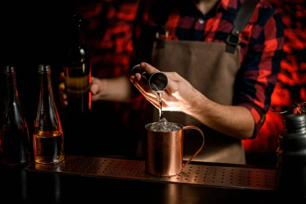 Camarero vierte cuidadosamente cóctel de jigger en la taza de metal . — Foto de Stock