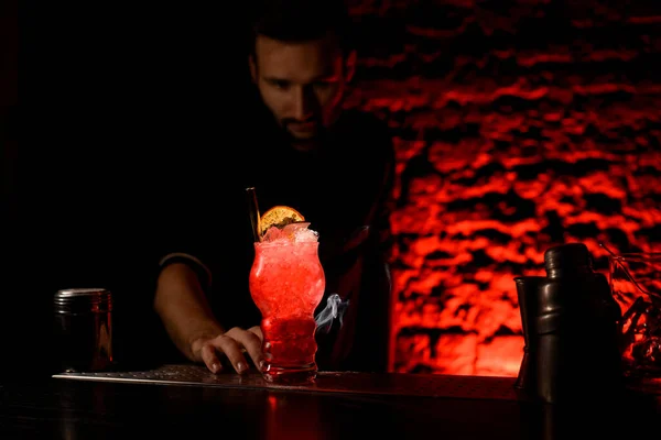 Verre avec cocktail lumineux décoré avec des tranches d'agrumes et tube de verre stand sur le bar — Photo