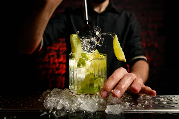 Gros plan barman expressivement mélanger cocktail en utilisant métal madler — Photo