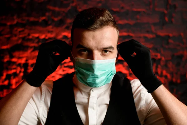 Primer plano. Retrato de un joven con máscara médica y guantes negros . — Foto de Stock