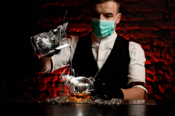 Camarero en máscara con guantes negros vierte cuidadosamente beber en frasco especial — Foto de Stock