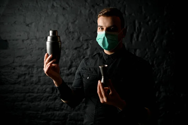 Man i mask med jigger och shaker i händerna står vid svart tegelvägg — Stockfoto