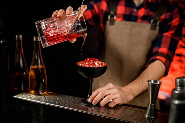 Cantinero macho precisa vierte campari rojo bebida de la taza de mezcla a la copa de vino — Foto de Stock