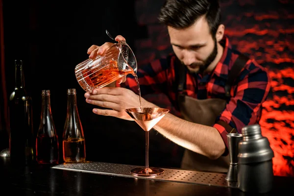 Camarero masculino vierte cuidadosamente cóctel de la taza de mezcla en vidrio de martini de metal . —  Fotos de Stock