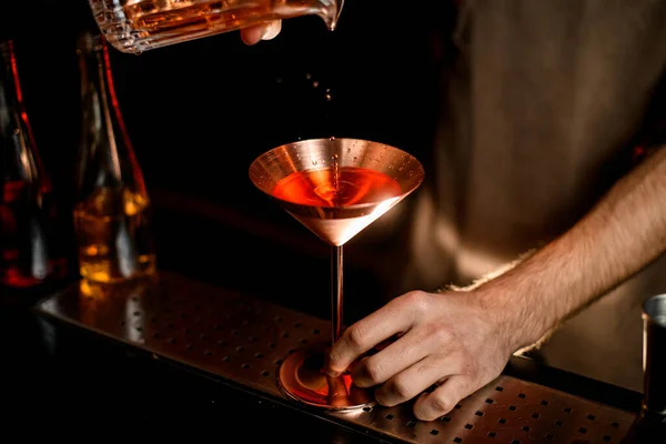 Närbild metall martini glas där bartendern häller cocktail. — Stockfoto