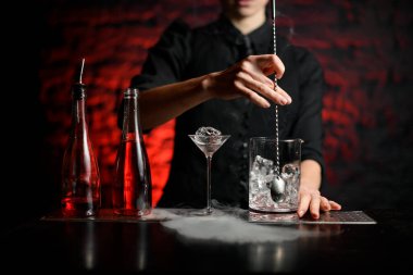 Barmen karıştırma bardağında uzun metal kaşık tutuyor.