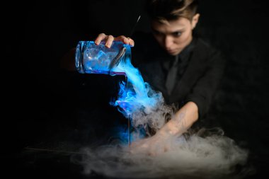 Profesyonel kadın barmen, martini bardağına karıştırılmış dumanlı kokteyl dolduruyor..