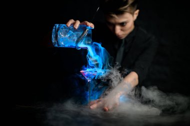 Kadın barmen profesyonel olarak martini bardağının içine karıştırdığı dumanlı kokteyli dolduruyor..