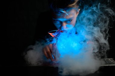 Dumanlı bar tezgahında kokteyl standı dolu aydınlatmalı martini bardağının yakın çekimi..