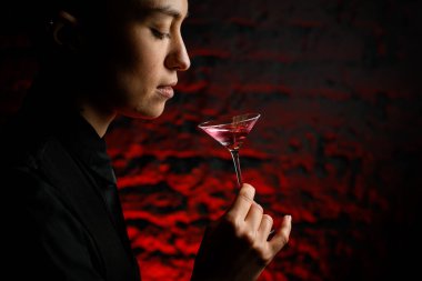 Elinde içkiyle martini bardağını tutan kızın yakın profil yüzü.