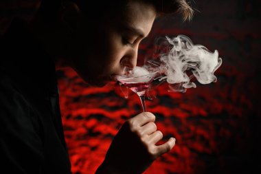 Elinde dumanlı martini bardağı tutan ve ondan içen kızın yakın profil yüzü..