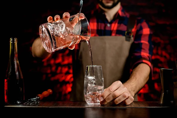 Barman profesional precisa vierte cóctel de la mezcla de la taza en un vaso pequeño . — Foto de Stock