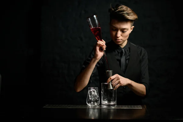 Barman feminino derrama magistralmente bebida alcoólica em metal jigger . — Fotografia de Stock