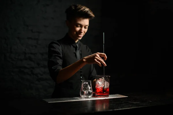 Jovem bartender mulher detém longa colher de metal e mix cocktail — Fotografia de Stock