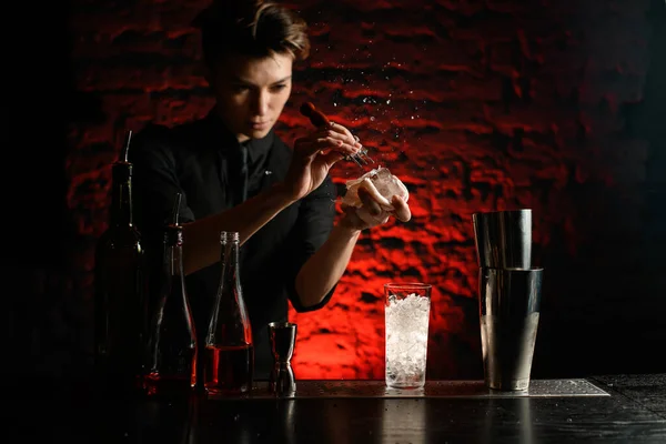 Jovem barman mulher em roupas pretas ativamente quebra gelo com dispositivo especial . — Fotografia de Stock
