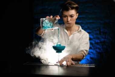 Kadın barmen, Smoky Bar 'da bardakları karıştırırken ustaca mavi kokteyl koyuyor.