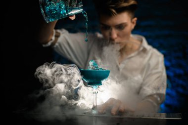 Yakın plan. Kadın barmen, Smoky Bar 'da bardağa karıştırırken mavi kokteyl döküyor ve şuna bak.